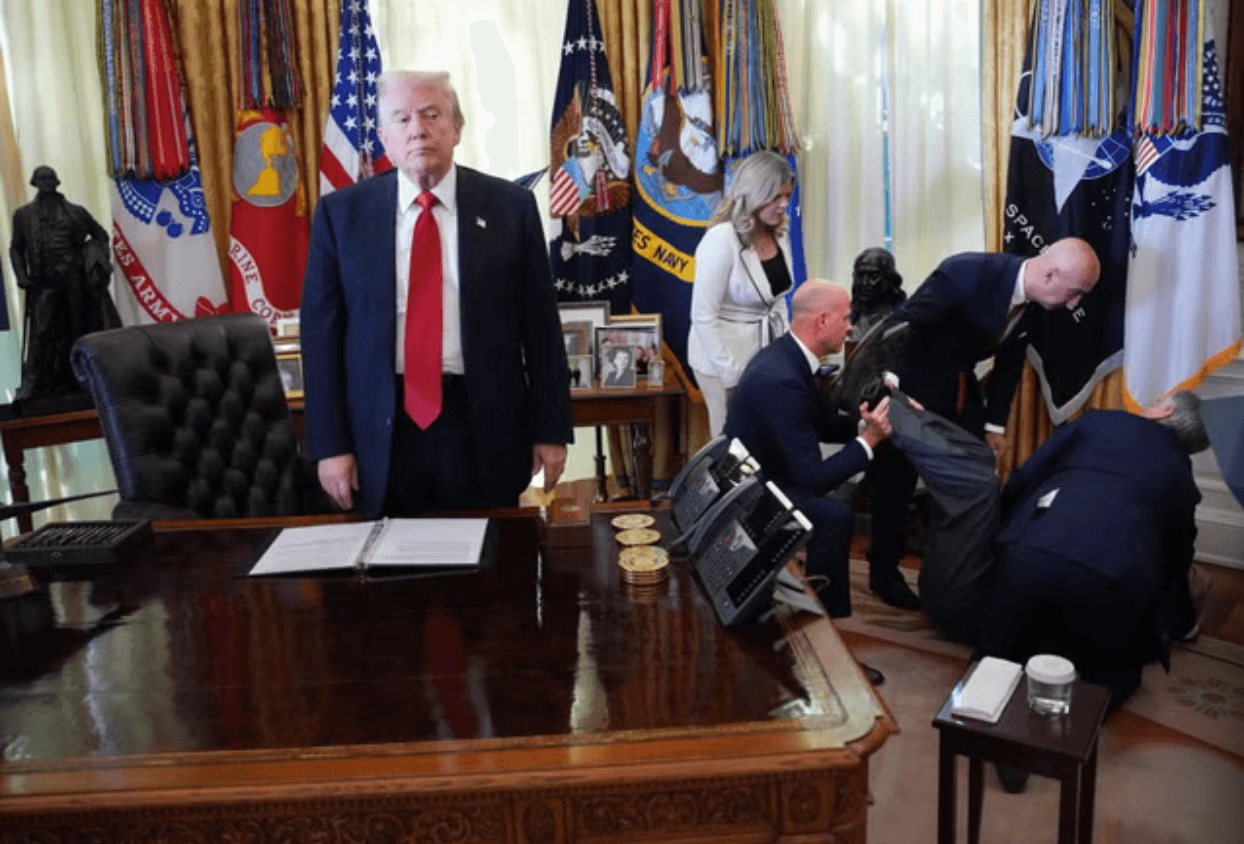President Trump stands in the Oval Office as aides and officials assist a pharmaceutical executive who collapsed during a press event announcing a new federal deal on weight-loss medications. 